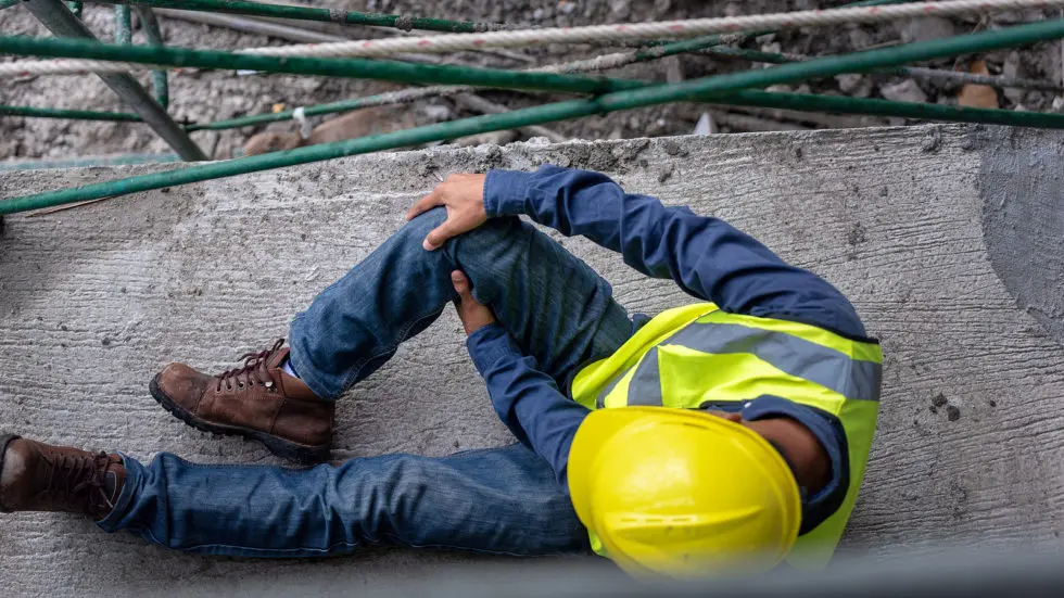 Injured construction worker holding his knee